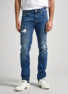 Men Mid Rise Slim Jeans WORN Medium Blue. Ανδρικό παντελόνι τζιν σε στενή γραμμή και μεσαίο καβάλο. Μέτριο μπλε με έντονες φθορές. Μαλακό και ελαστικό ύφασμα. Νεανικό και casual ύφος.