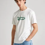 Men Cotton Regular Logo T-Shirt CLAUDE Off White. Ανδρικό μακό μπλουζάκι με κοντό μανίκι και στρόγγυλο λαιμό. Μαλακό και ελαφρύ βαμβακερό ύφασμα που αναπνέει. Casual outfit σε κάθε εποχή. Ιδανικός συνδυασμός denim & cotton chinos παντελόνια. PRODUCT DETAILS - Cotton jersey T-shirt – Regular Fit - Short sleeves - Crew neck - PEPE JEANS logo printed on chest- Ribbed detail on the neck - Double stitching on sleeves and hem - Inner neck band with printed logo - Made of 100% sustainable cotton. Sustainable cotton minimises the use of harmful chemicals, improves soil quality, and prevents contamination to help protect the health of growers and local wildlife.